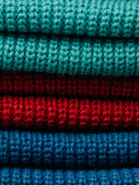 Gestapelte Strickpullover in Türkis, Rot und Blau